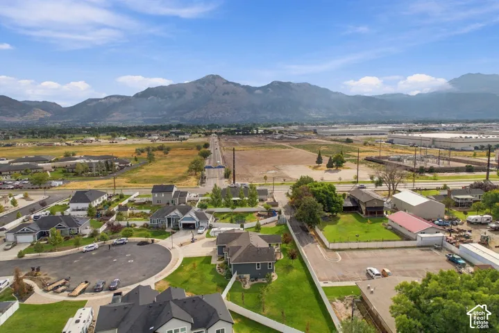 Expansive mountainous backdrop, residential area with established homes, cul-de-sac street design, broad open land, and distant commercial structures
