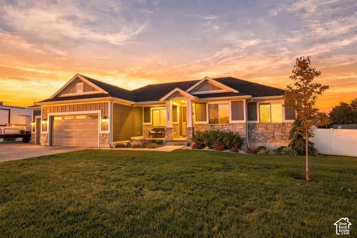 Siding exterior with stone accents, attached two-car garage, covered front entry, and front yard landscaping