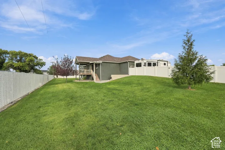 Expansive green lawn with a sloped grade, featuring perimeter chain-link and privacy fencing