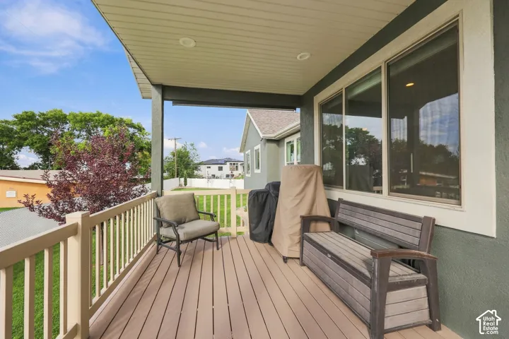 Covered outdoor deck with wood-finish decking, light-toned railing, and a stucco exterior wall