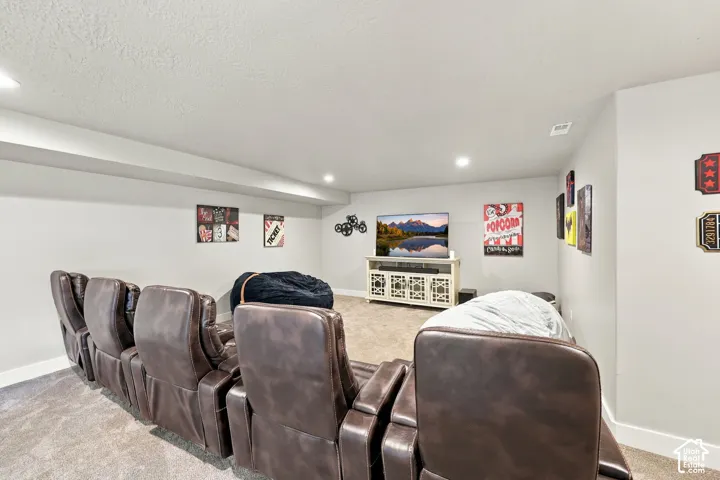 Spacious entertainment area with recessed lighting, light gray walls, and carpet flooring