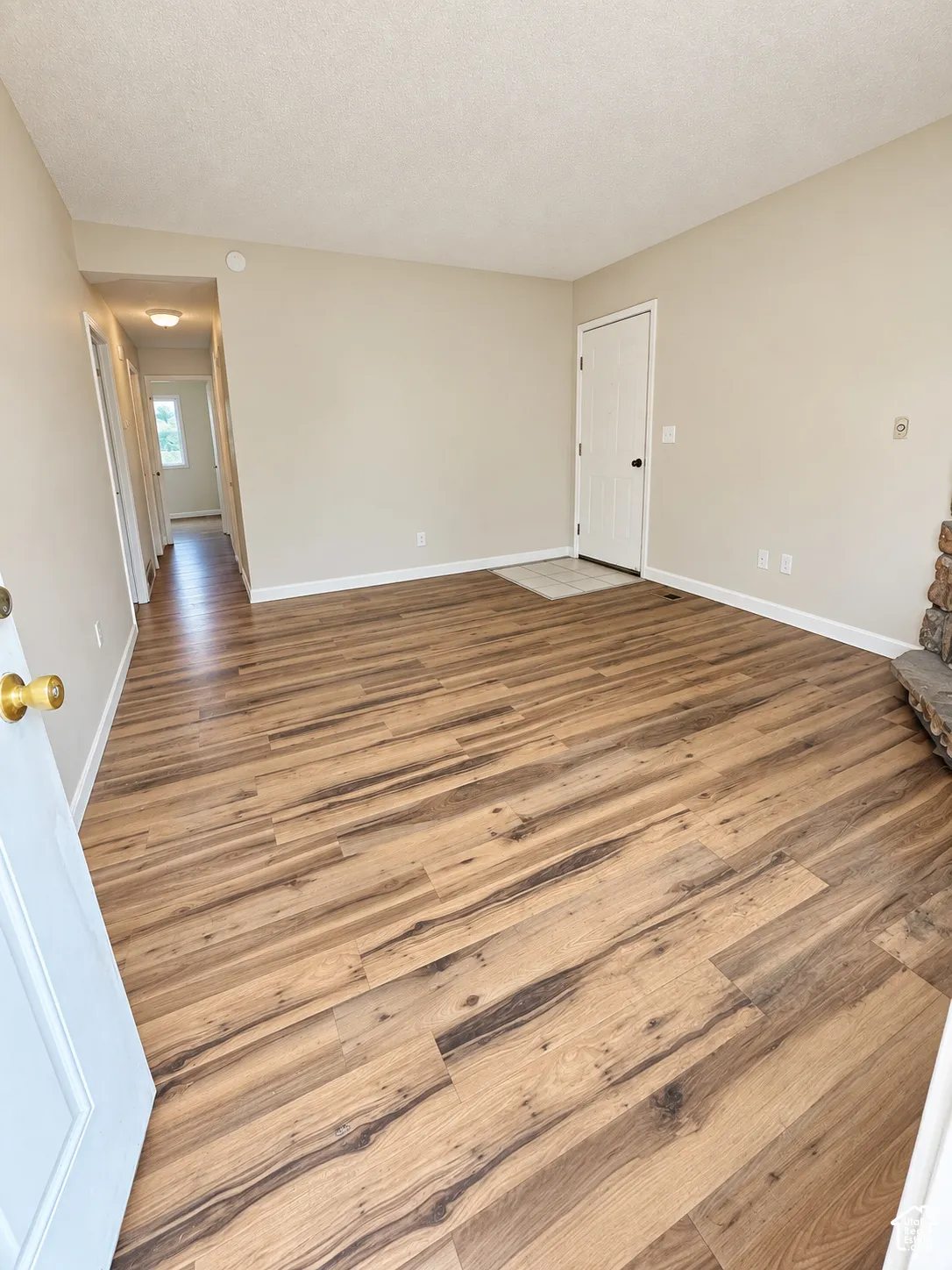LVP flooring, neutral wall paint, white trim, and a stone-clad fireplace