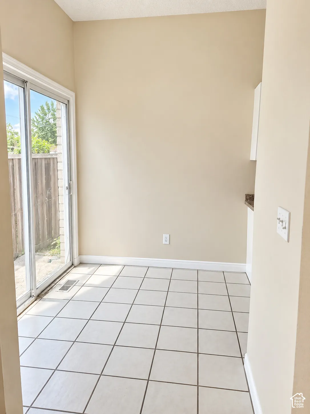 Sliding glass door, tiled flooring, wood fence, upper cabinet, and countertop