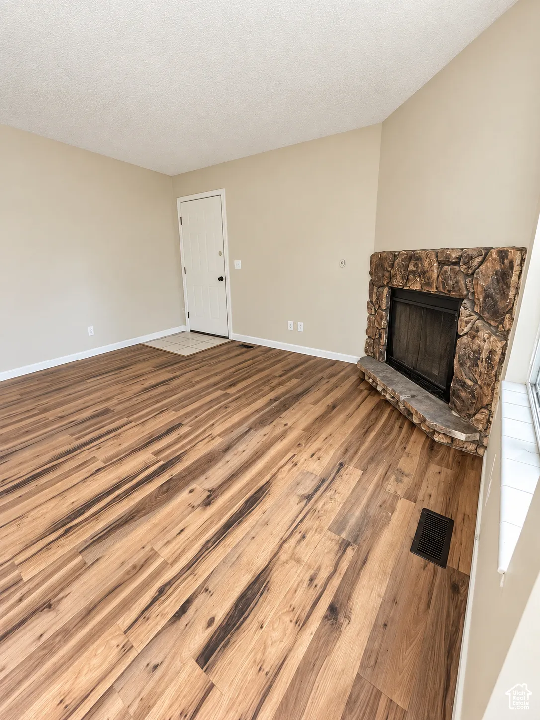 LVP flooring throughout, stone-clad fireplace, vaulted ceiling, and neutral wall tones
