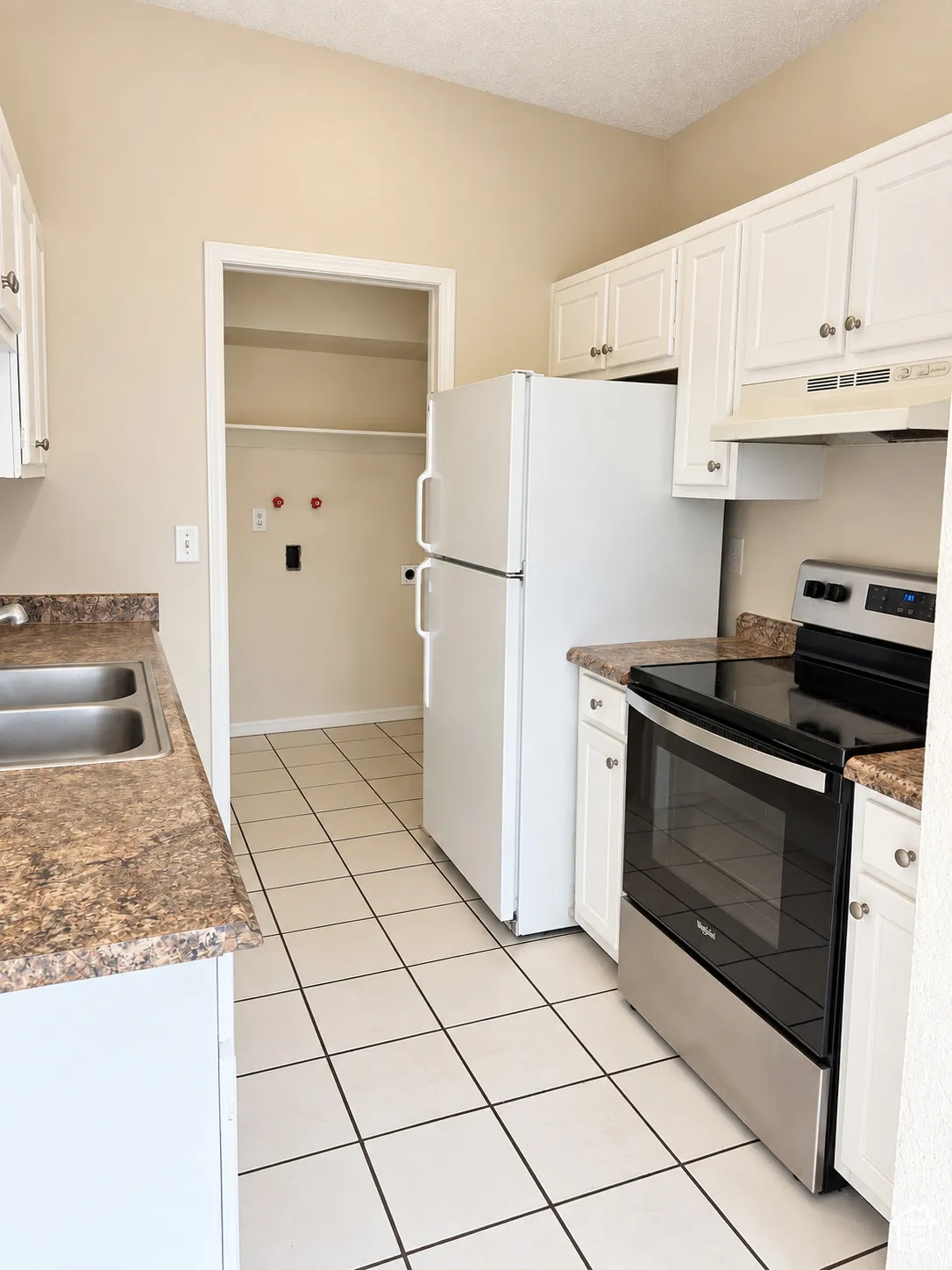 Kitchen featuring white cabinetry, a stainless steel range, a double basin sink, and tile flooring