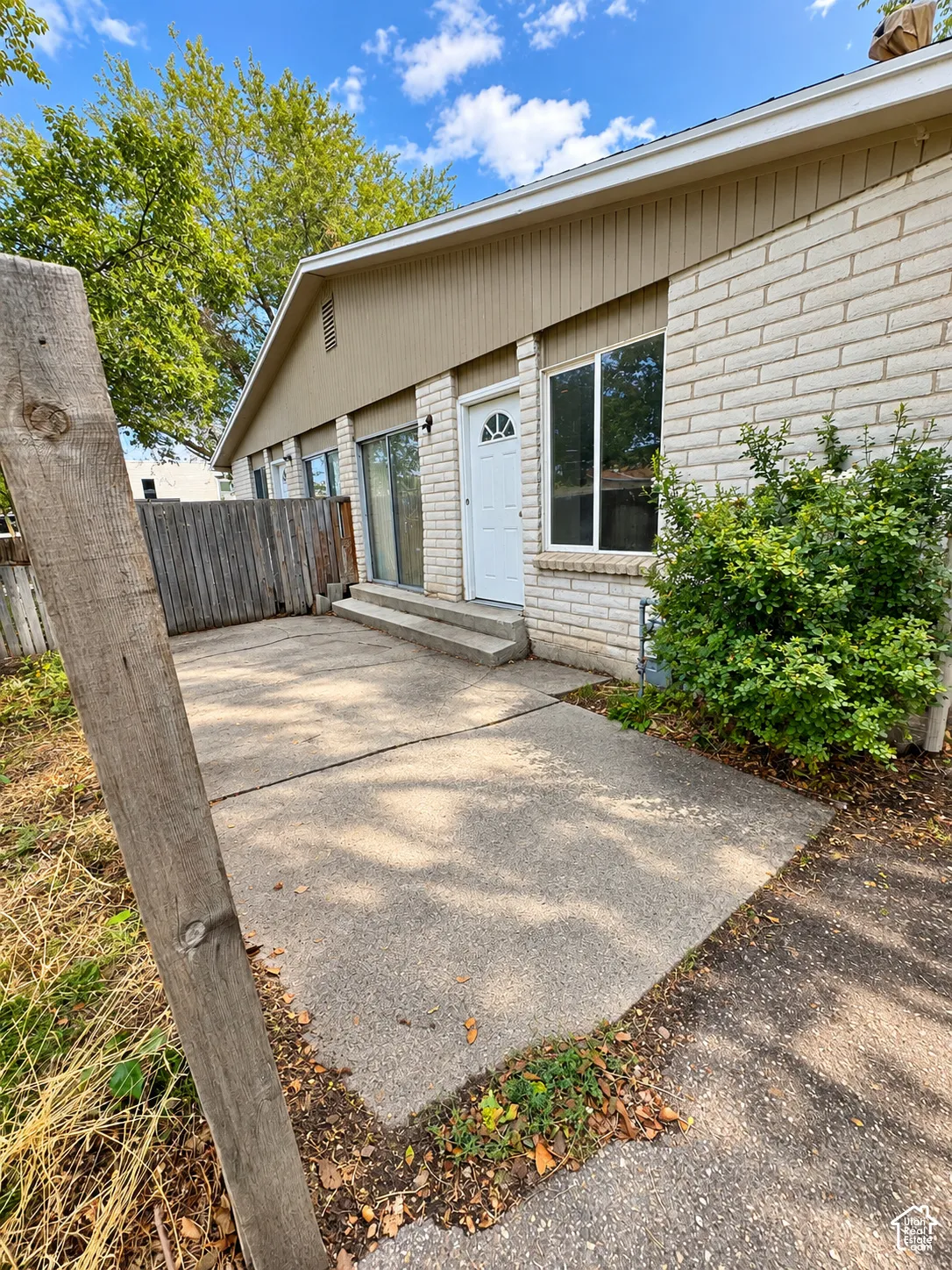 Brick and siding exterior with a white entry door, large windows, and a concrete patio