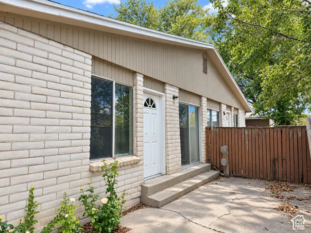Brick exterior with vertical siding accents, multiple windows, and a wood privacy fence