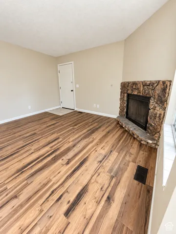LVP flooring throughout, stone-clad fireplace, vaulted ceiling, and neutral wall tones