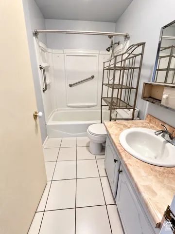 Tile flooring, vanity with integrated sink, shower-tub combination, wall-mounted mirror, and cabinet storage
