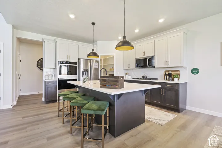 Spacious kitchen featuring an expansive center island, integrated stainless steel appliances, two-tone cabinetry, and wood-finish flooring