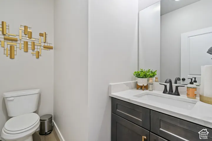 Vanity with a white countertop and integrated sink, dark wood-finish cabinetry, and matte black fixtures