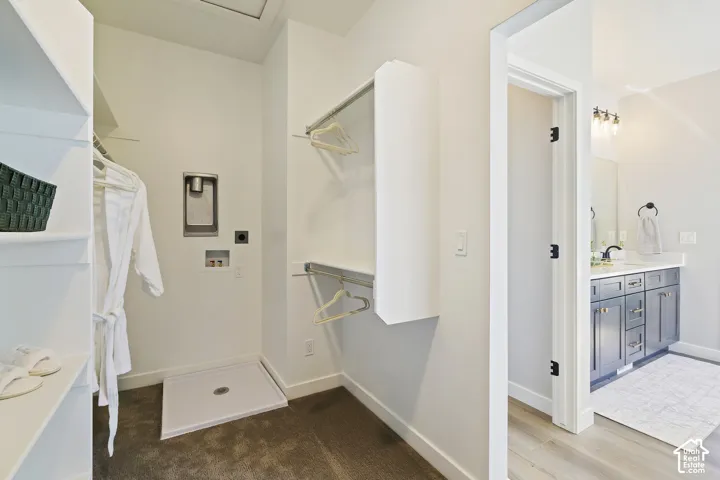 Walk-in closet featuring built-in shelving, hanging rods, and washer/dryer hookups