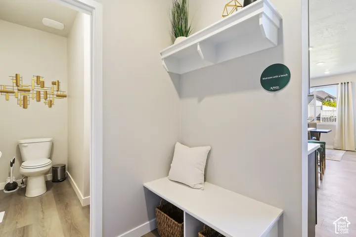 Built-in shelving with integrated bench seating, wood-finish flooring, and a powder room with a white toilet