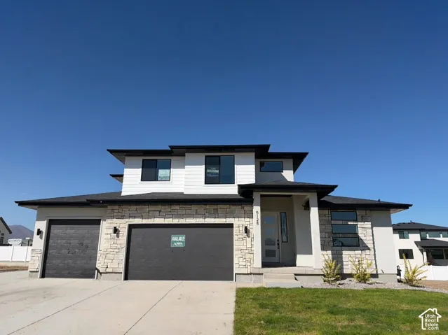 Contemporary facade with stone and siding accents, prominent flat rooflines, dark-framed windows, and a two-car garage