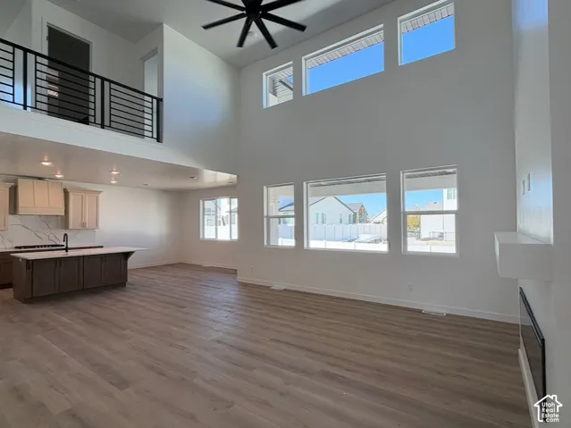 Open concept living area with high ceilings, featuring a built-in electric fireplace and wood-finish flooring