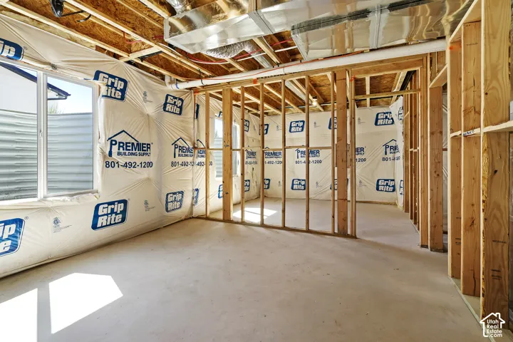 Unfinished basement with framed walls, exposed ceiling joists, and a concrete floor