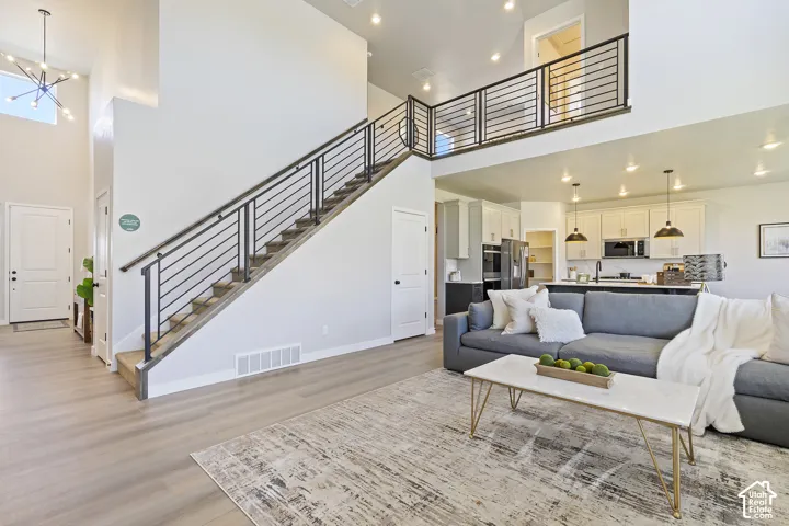 Open-concept living area featuring a two-story ceiling, light wood-finish flooring, and a modern stair railing