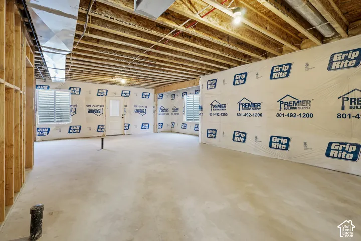 Unfinished basement space featuring exposed wood framing, concrete flooring, and visible ductwork
