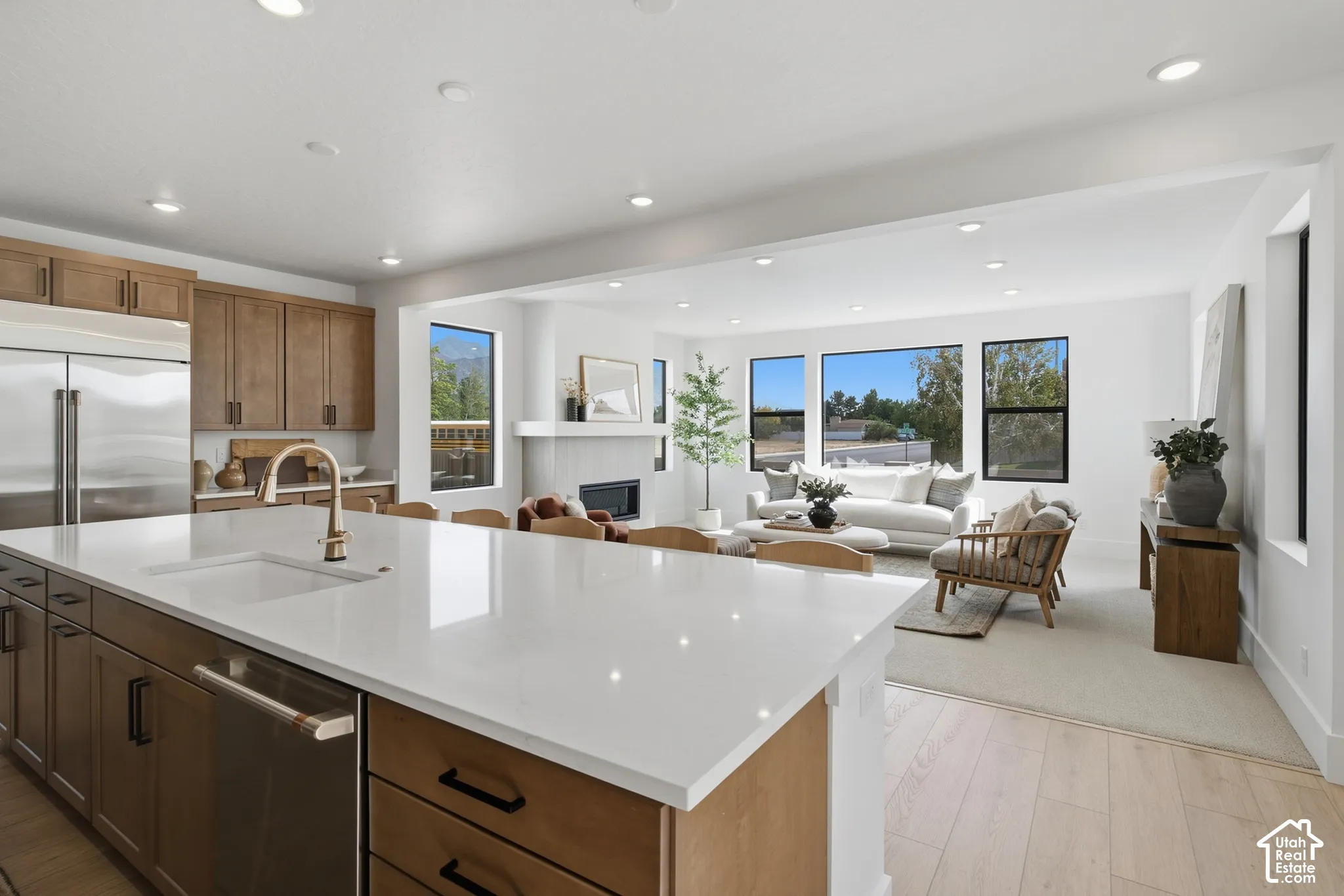 Kitchen island with a white solid surface countertop and undermount sink, stainless steel appliances, and recessed lighting