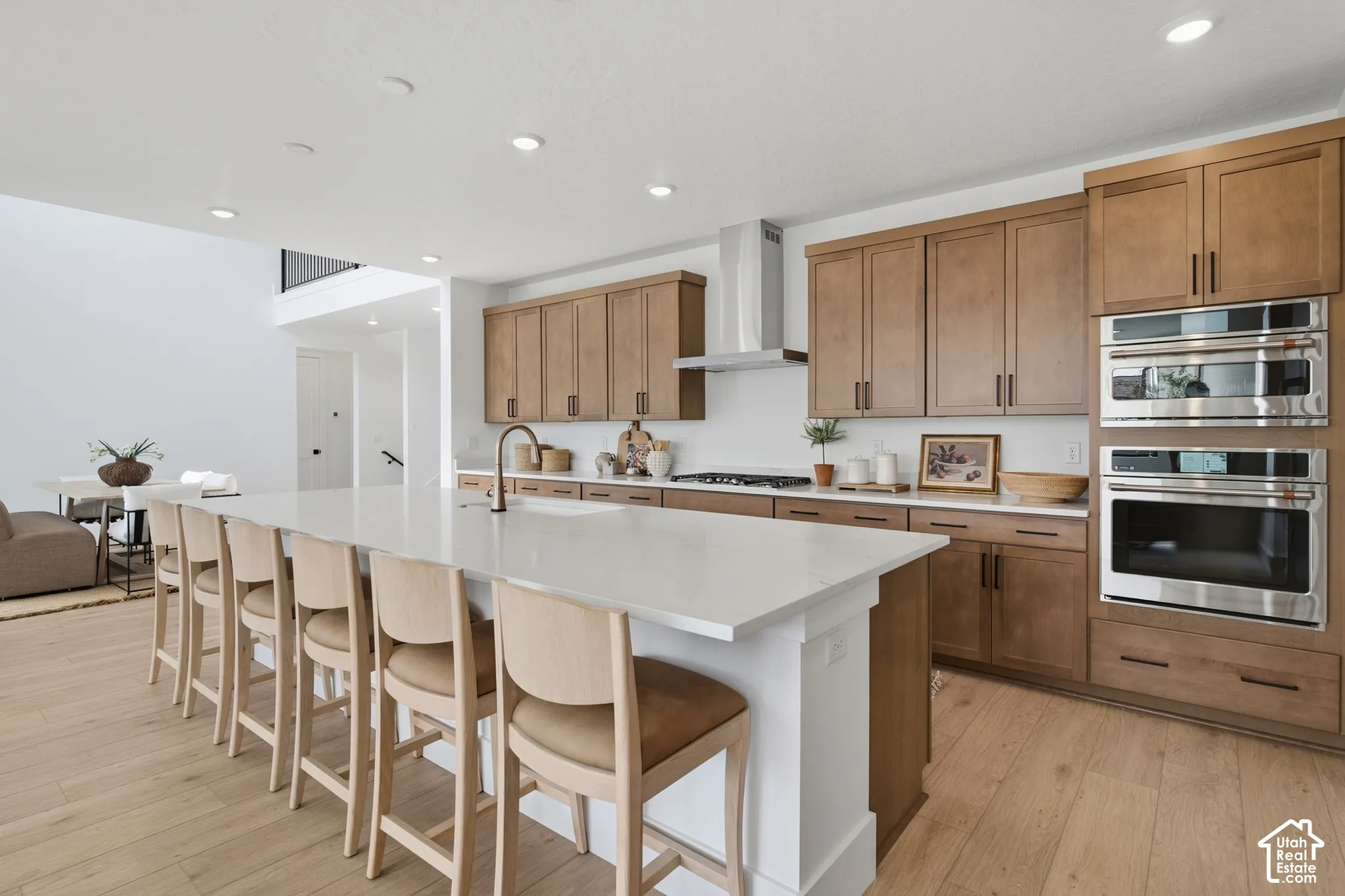 Expansive kitchen island with a light-toned countertop, LVP flooring, built-in stainless steel oven, and recessed lighting
