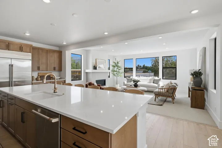 Kitchen island with a white solid surface countertop and undermount sink, stainless steel appliances, and recessed lighting