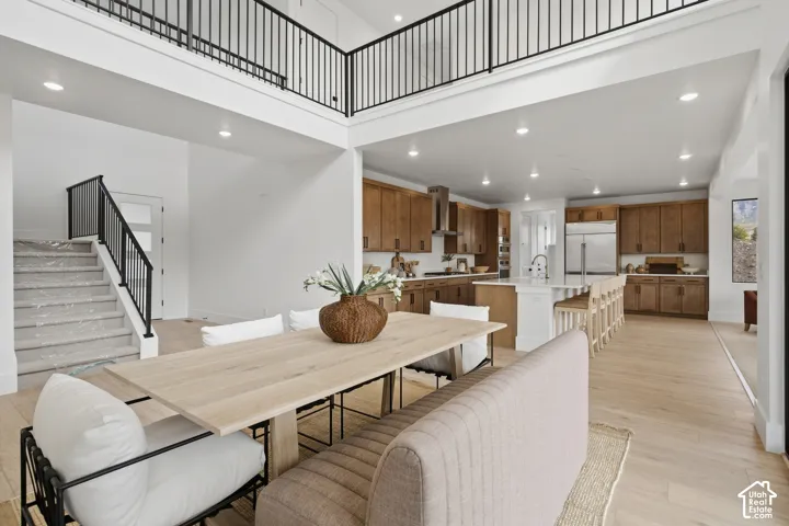 Open-concept living space with light wood-finish flooring, a kitchen featuring wood cabinetry and stainless steel appliances, and a central kitchen island with seating