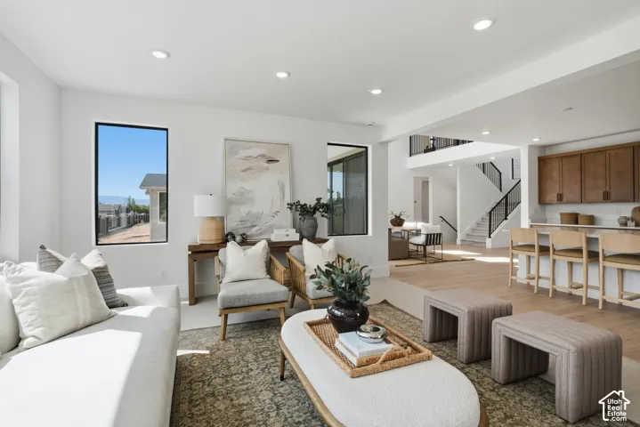 Recessed lighting, wood-finish flooring, white walls, black-framed windows, and built-in cabinetry with light countertops