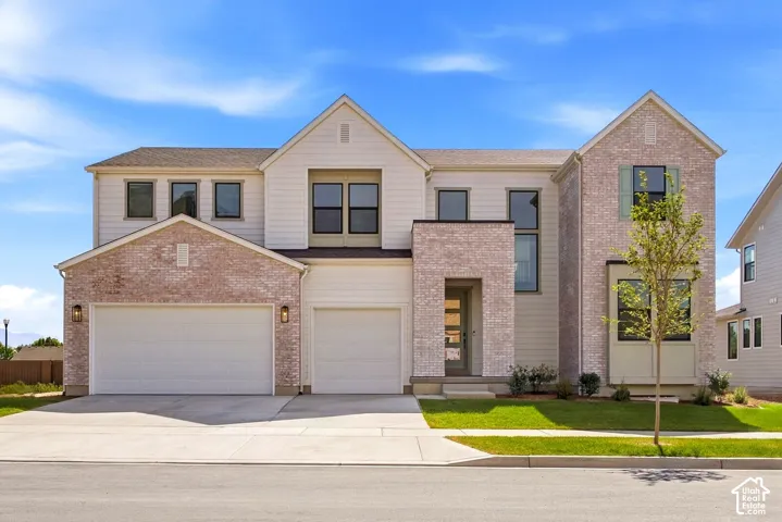 Contemporary architectural style featuring a multi-story facade, light-toned brick accents, vertical siding, a three-car garage, and a concrete driveway