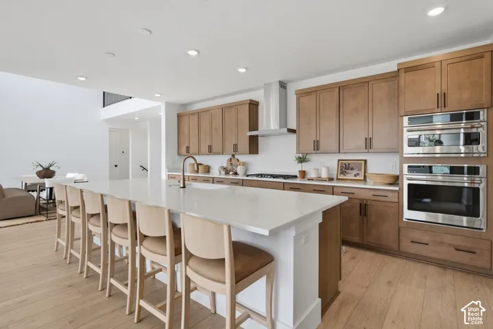 Expansive kitchen island with a light-toned countertop, LVP flooring, built-in stainless steel oven, and recessed lighting