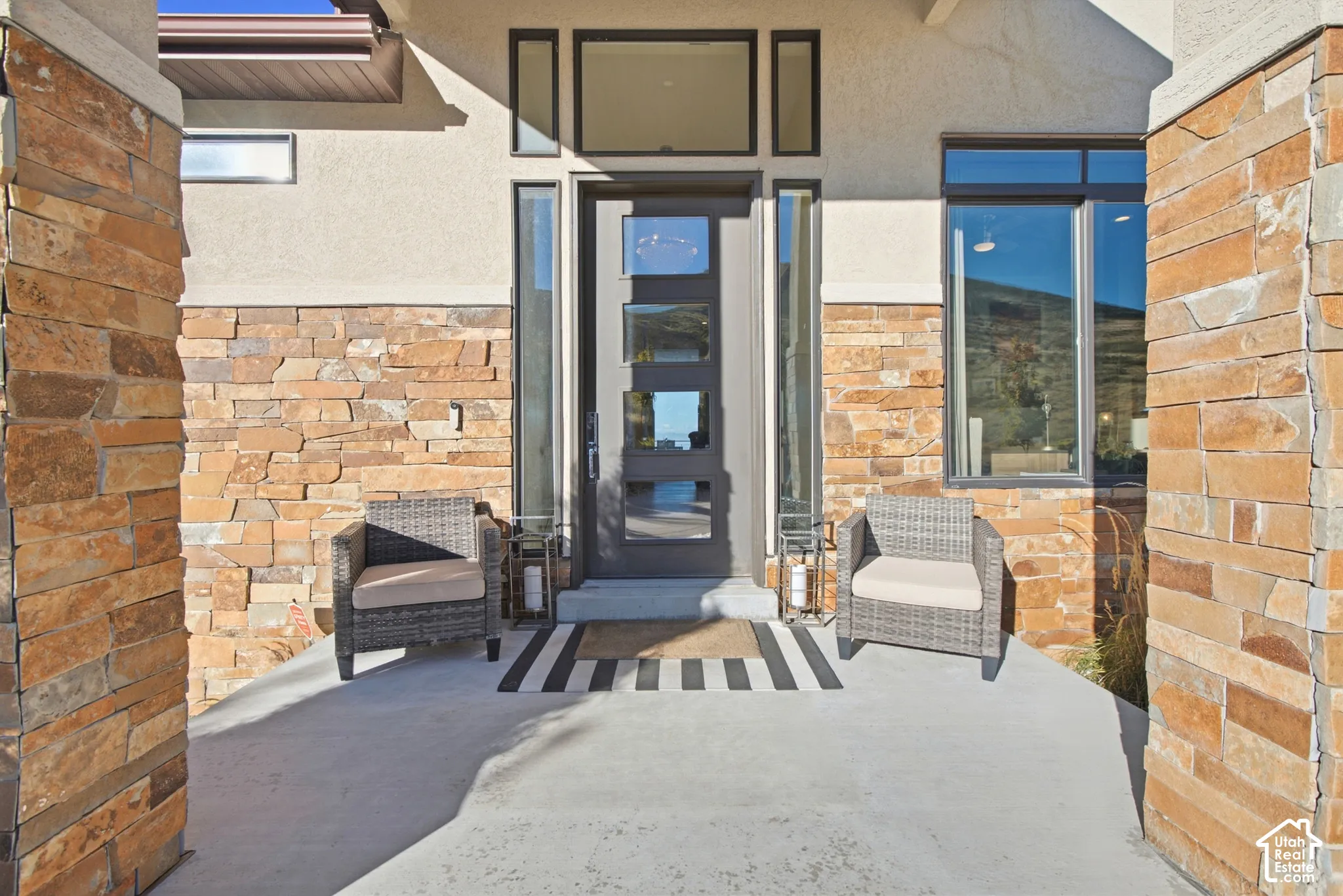 Modern entryway featuring a solid panel door with multiple glass inserts, full-length sidelights, and stacked stone accents