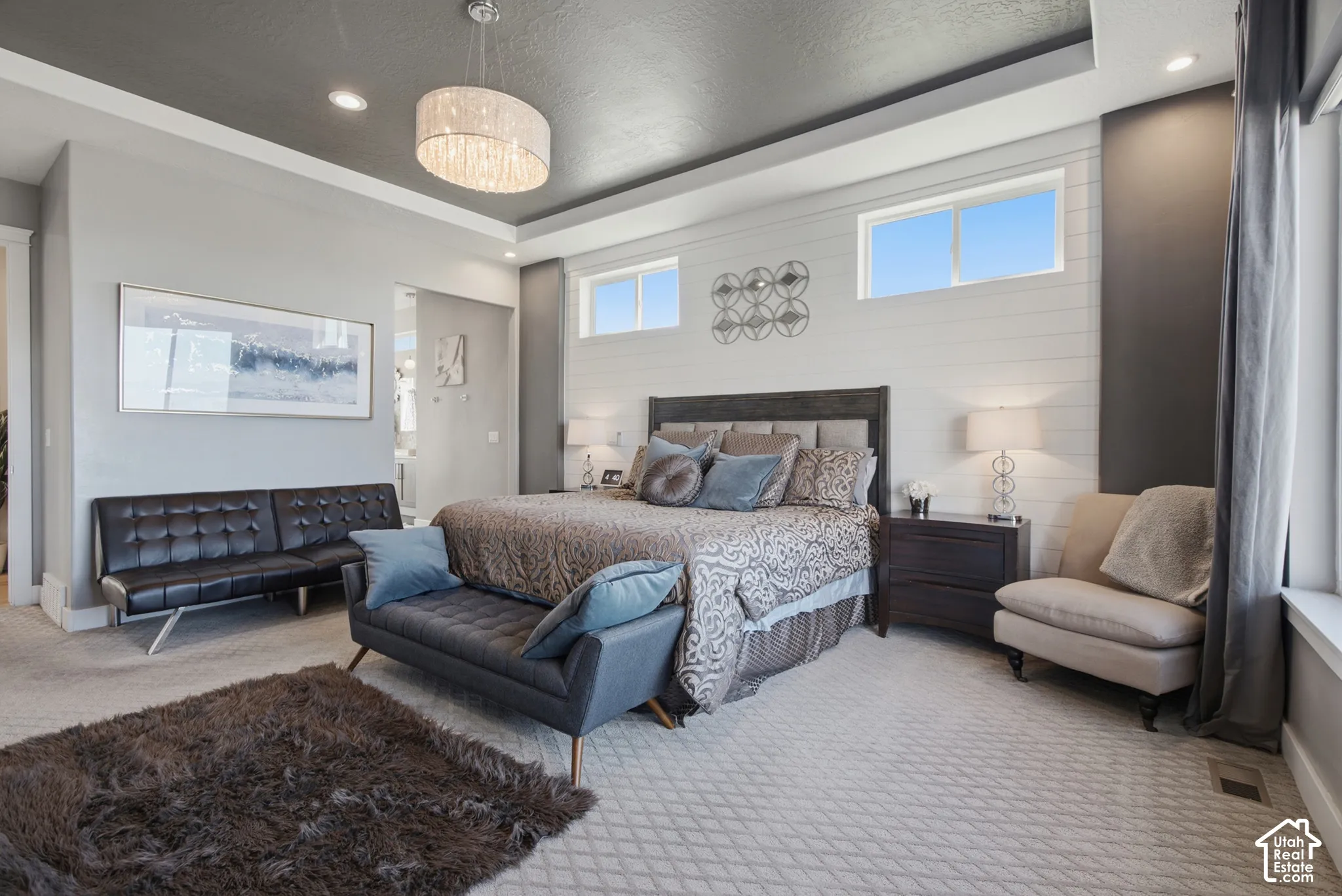 Recessed lighting, tray ceiling, shiplap accent wall, chandelier, and multiple windows