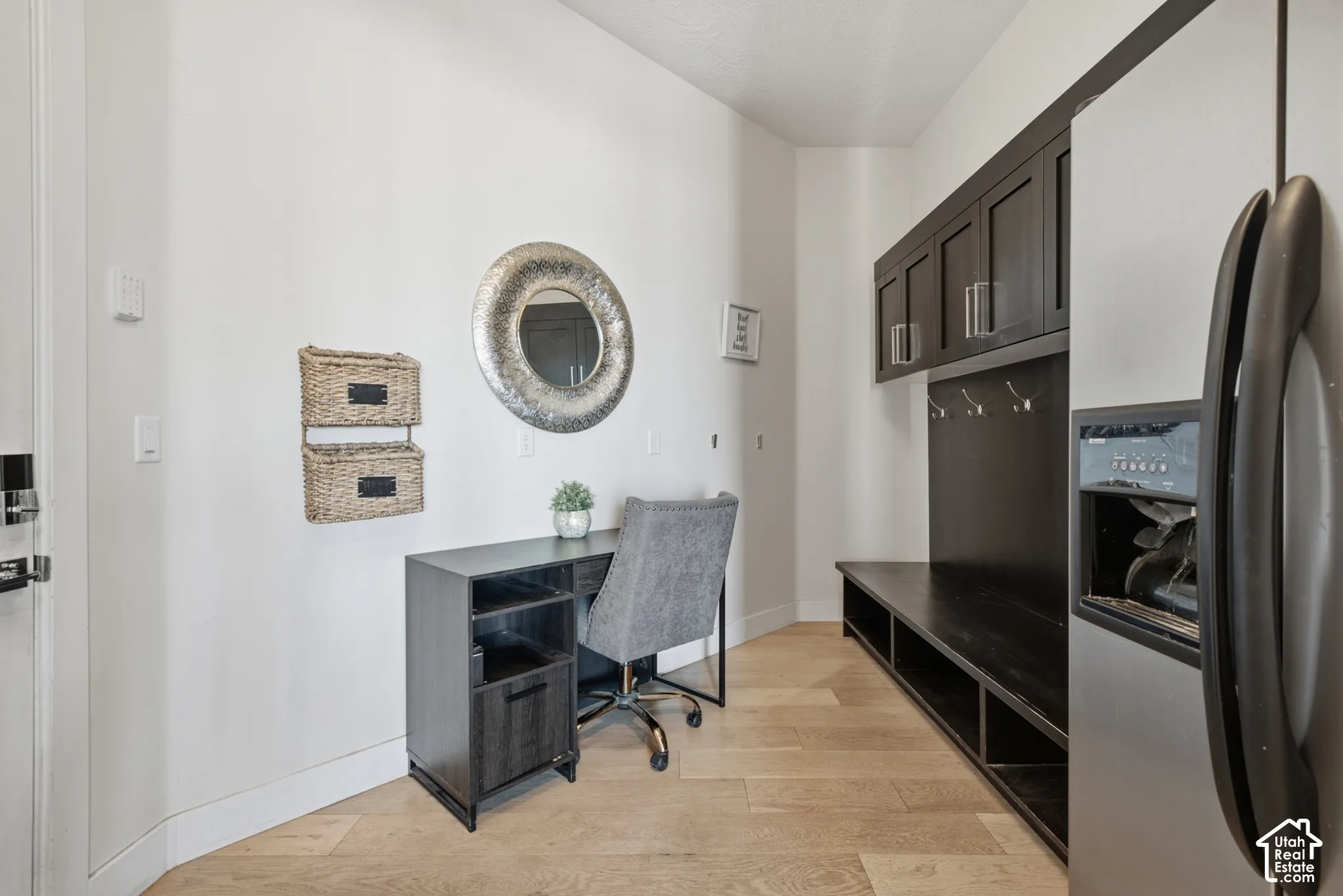 Wood-finish flooring, built-in dark wood cabinetry, dark wood built-in bench seating, dark wood desk, and stainless steel refrigerator