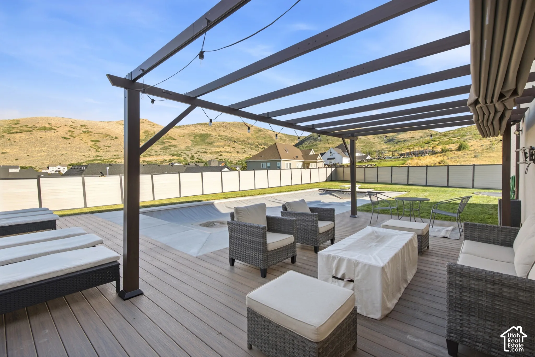 Expansive outdoor deck featuring a dark-toned pergola and a covered pool area