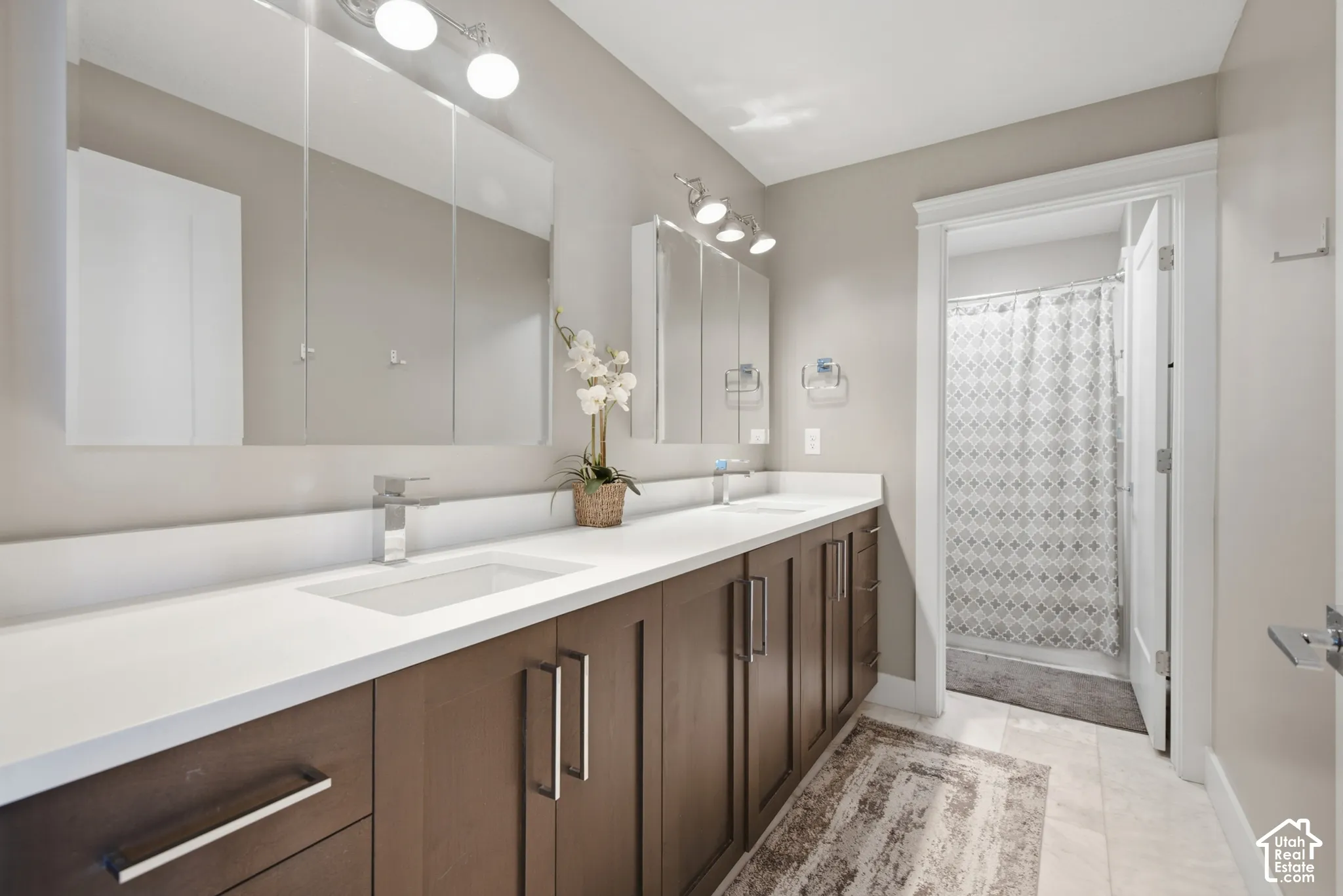 Double vanity with integrated sinks, contemporary chrome faucets, and dark wood-finish cabinetry