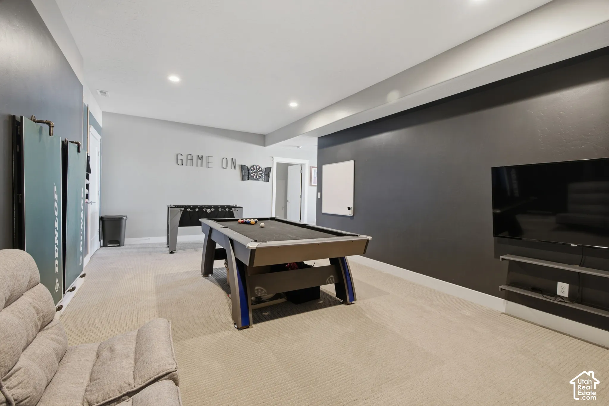 Carpeted recreation area featuring recessed lighting, a dark accent wall, and a built-in media shelf