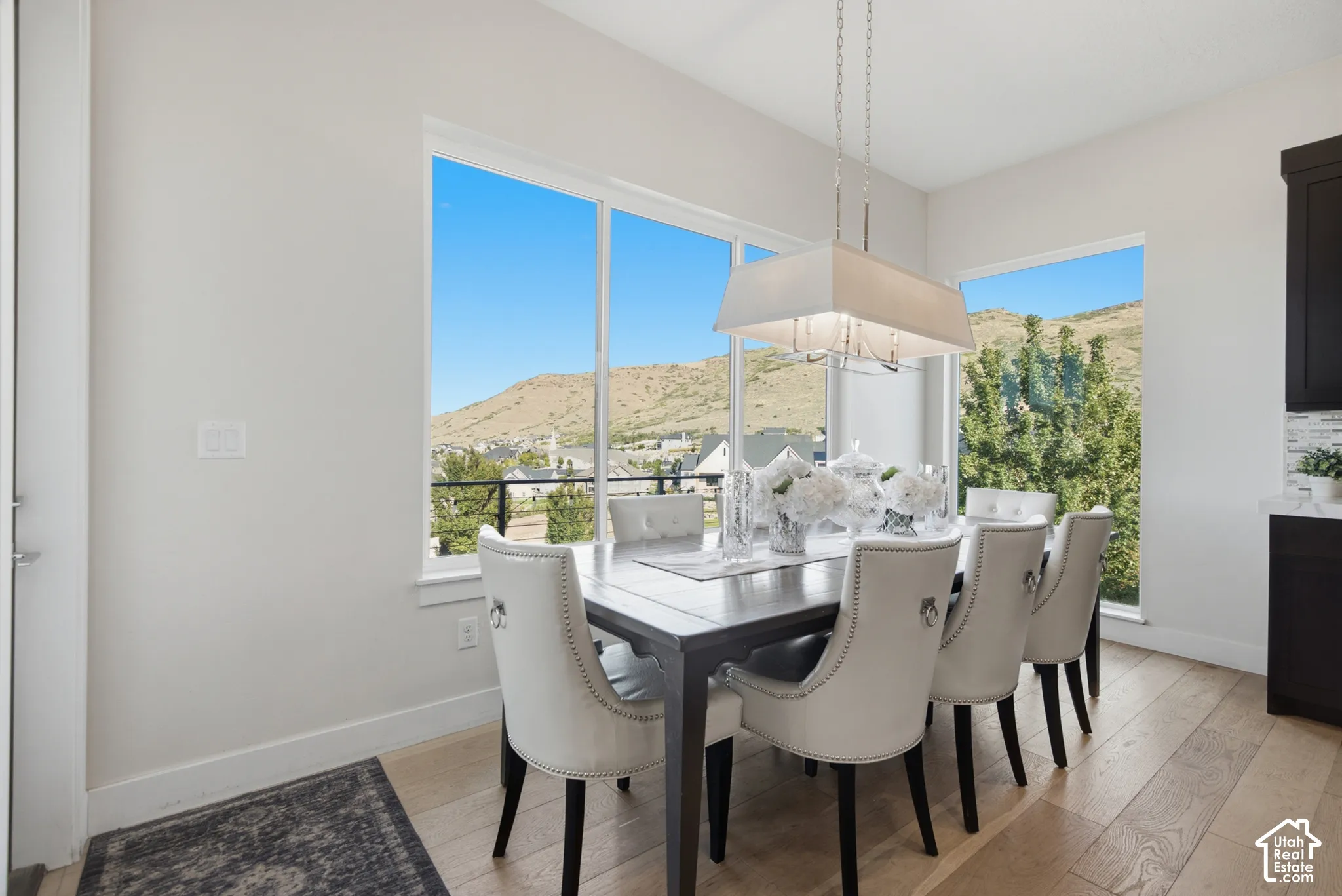 Recessed lighting, wood-finish flooring, and a contemporary linear chandelier illuminate the space