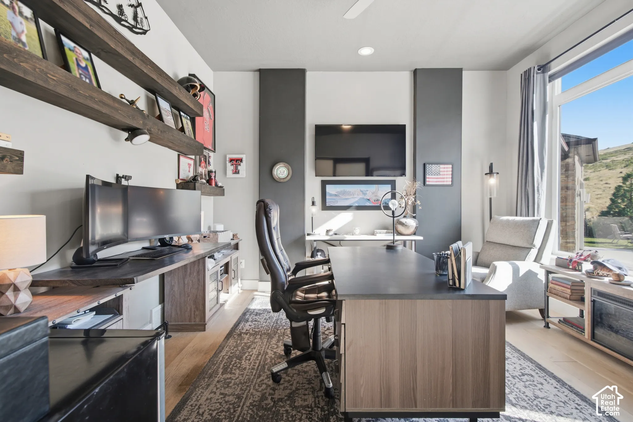 Wood-finish flooring with a large window and custom built-in shelving
