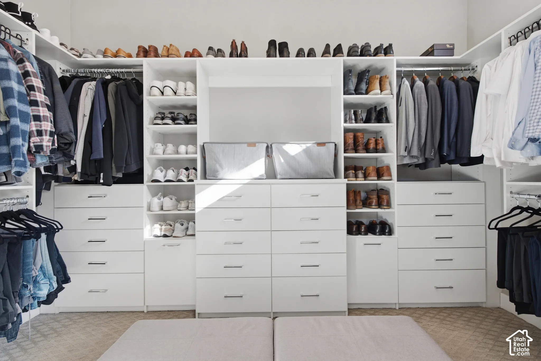 Custom closet system featuring white cabinetry, integrated shelving, hanging rods, and multiple drawers