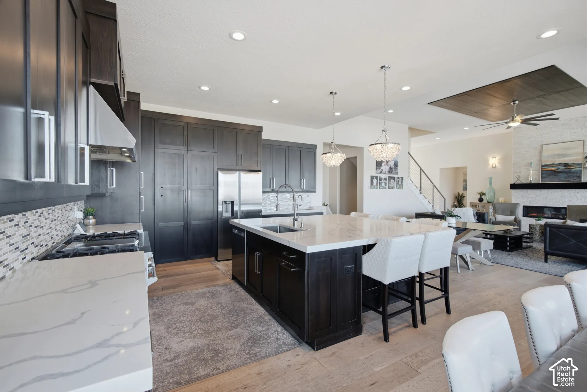 Open concept living space featuring a spacious kitchen island with seating, stainless steel appliances, and wood-finish flooring