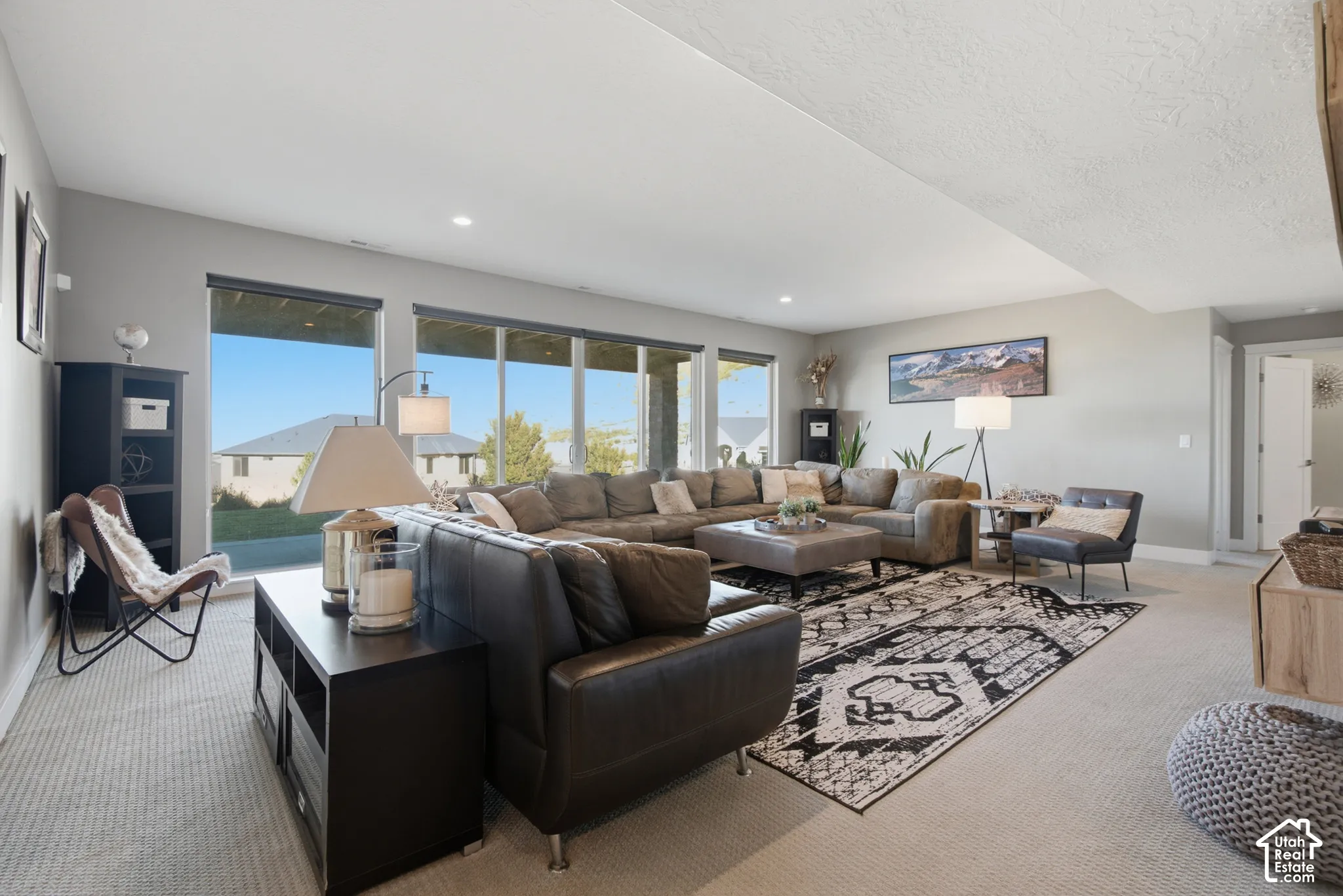 Expansive living area with large windows, light gray walls, and recessed lighting