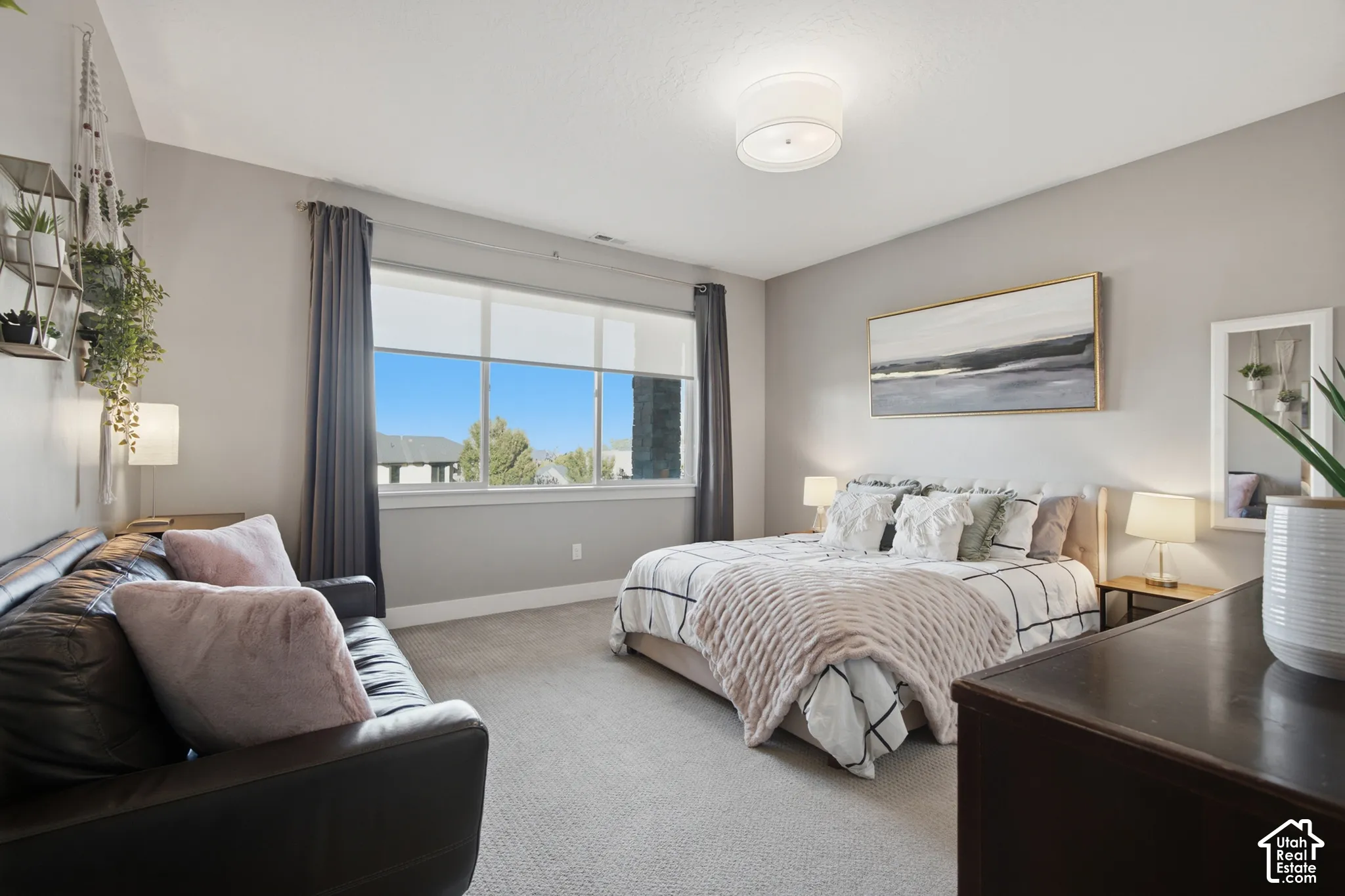 Spacious room featuring broad windows with roller shades, neutral tone carpeting, and a flush mount ceiling light fixture