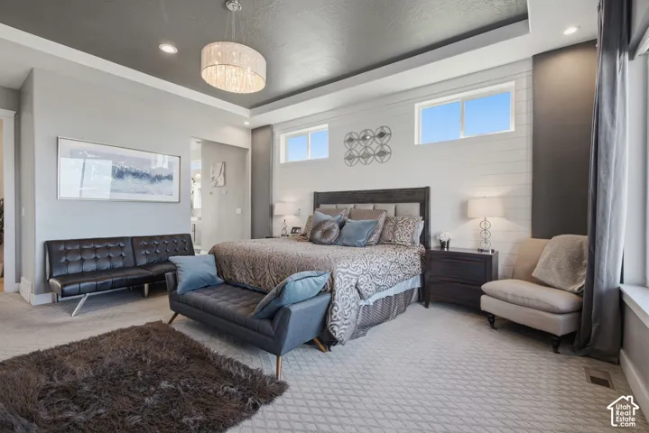 Recessed lighting, tray ceiling, shiplap accent wall, chandelier, and multiple windows