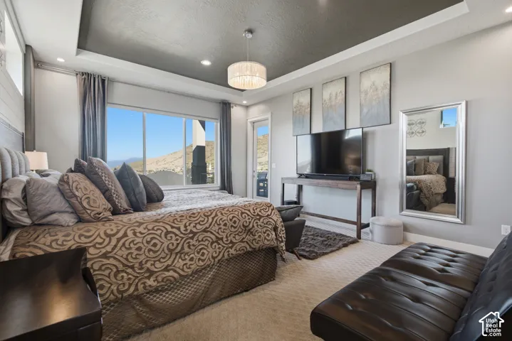 Expansive window with mountain backdrop, tray ceiling with recessed lighting, shiplap accent wall, and ceiling-mounted chandelier