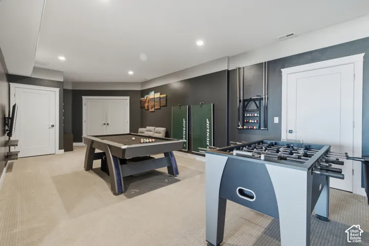 Recessed lighting illuminates a spacious room featuring carpeting, multiple entryways with white doors, and a neutral color palette
