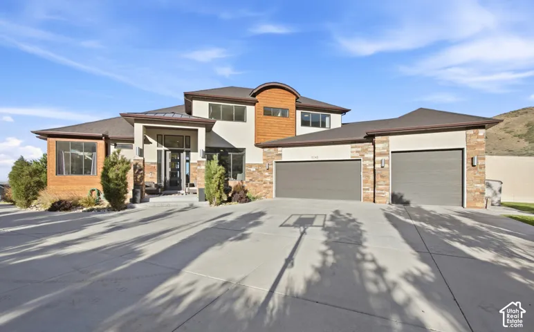 Contemporary exterior featuring stone accents, a multi-car driveway, and a two-car garage