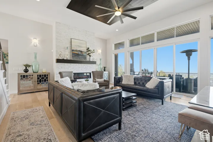 Living area featuring wood-finish flooring, a linear fireplace with a textured stone surround, and a dark wood mantel