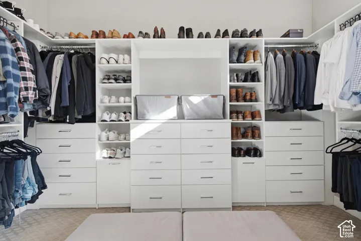 Custom closet system featuring white cabinetry, integrated shelving, hanging rods, and multiple drawers
