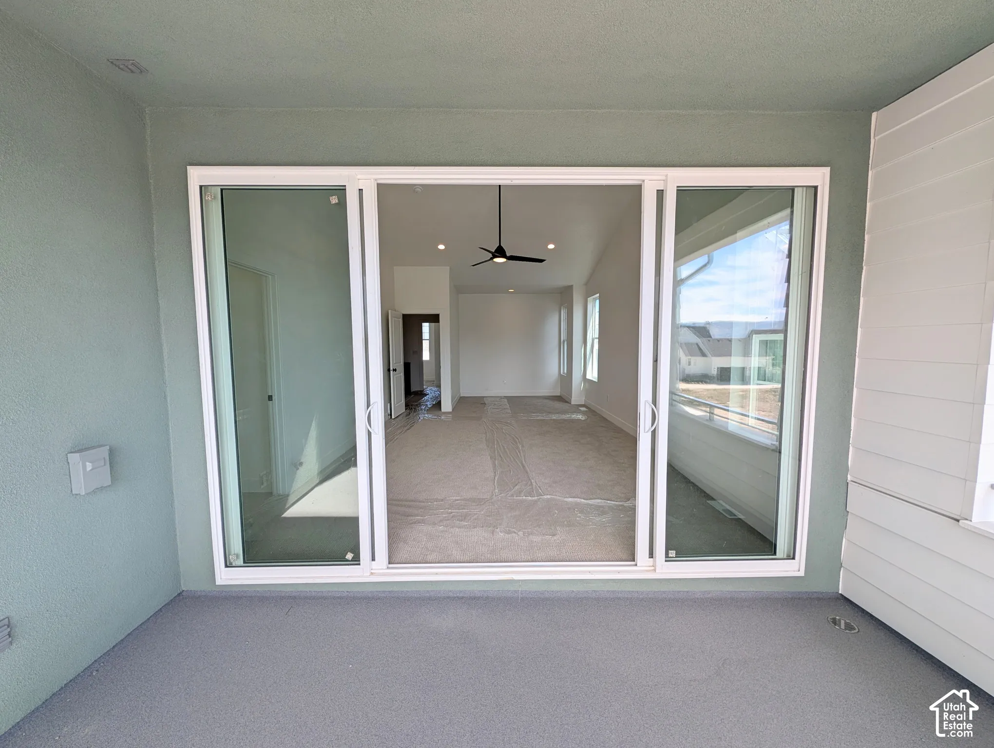 Sliding glass door entry to interior space with vaulted ceiling and ceiling fan