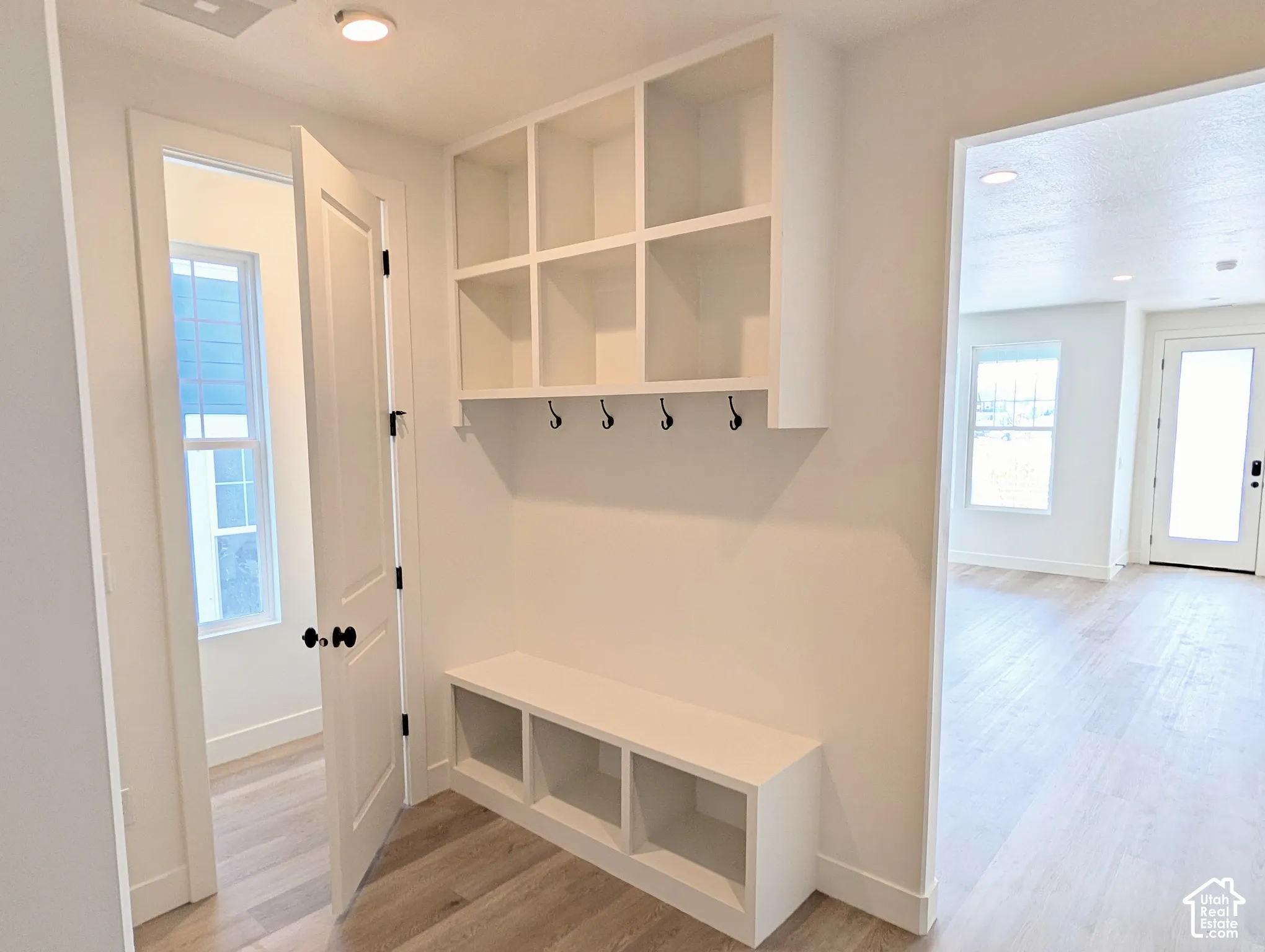 Entryway mudroom with built-in bench seating, integrated storage cubbies, and overhead shelving