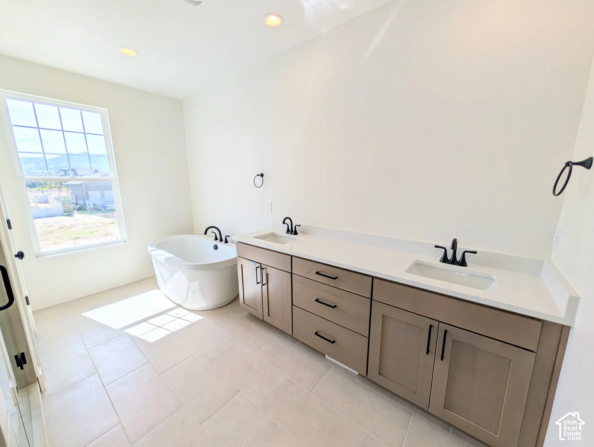 Dual vanity with integrated sinks, light-toned cabinetry, light-colored countertops, and matte black fixtures